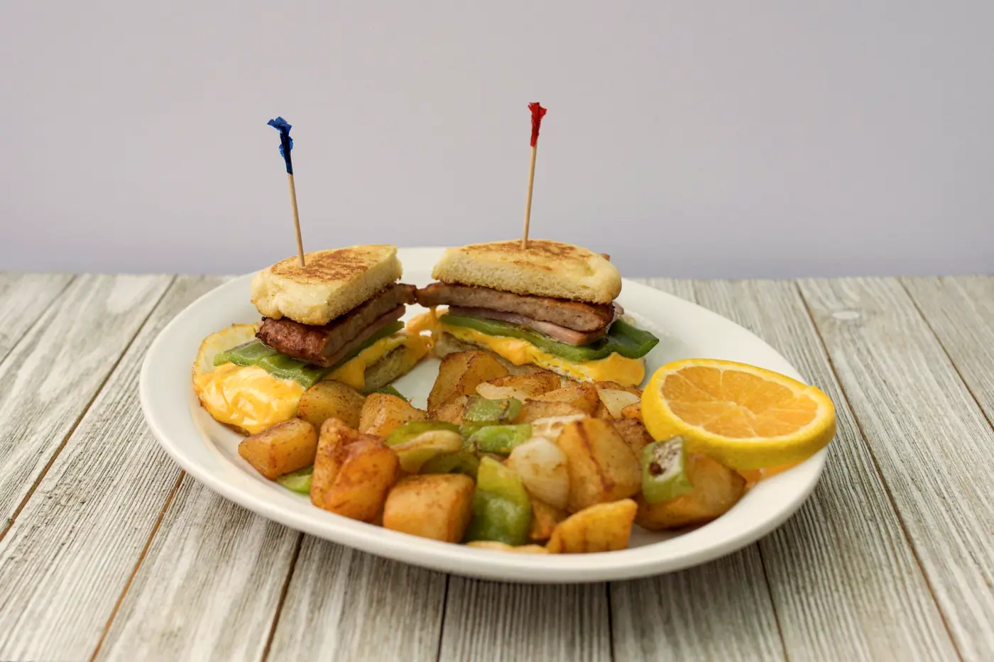 Grilled breakfast sandwich with home fries, peppers and an orange slice