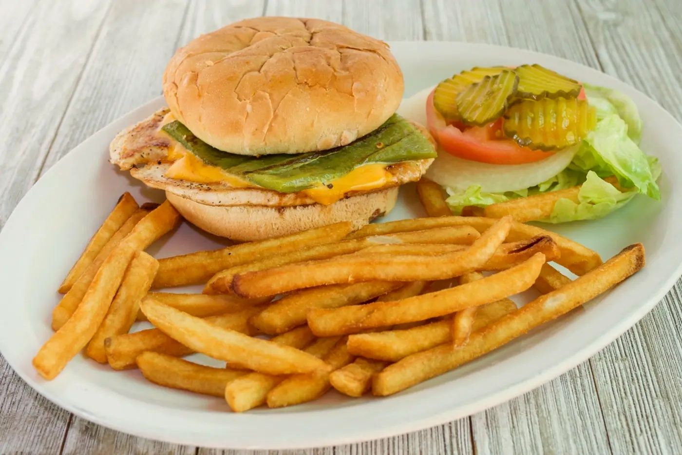 Grilled chicken sandwich with green chile and cheese, pickles and fries