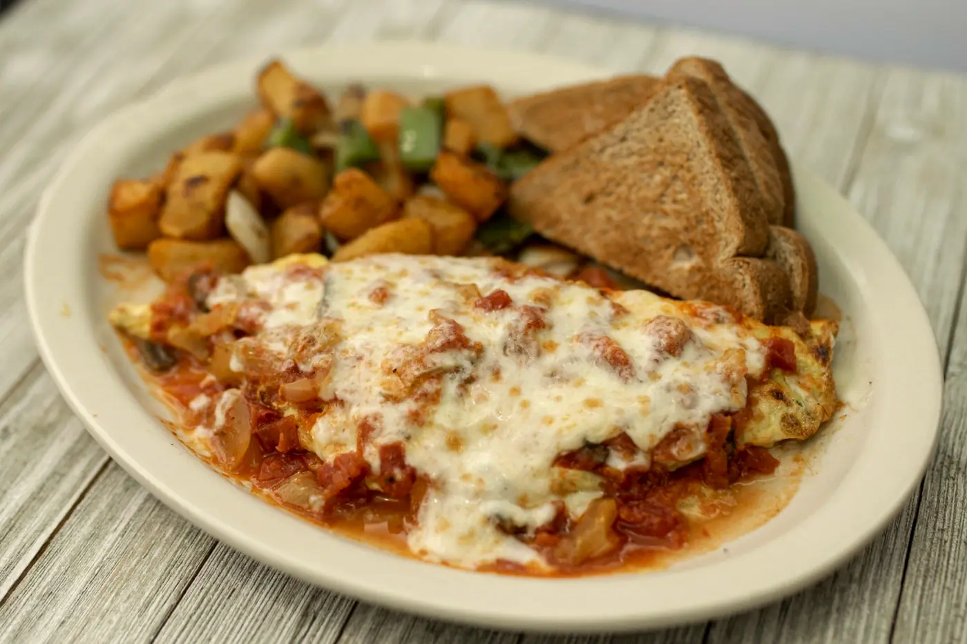 Omelette smothered in salsa and melted cheese with breakfast potatoes and toast